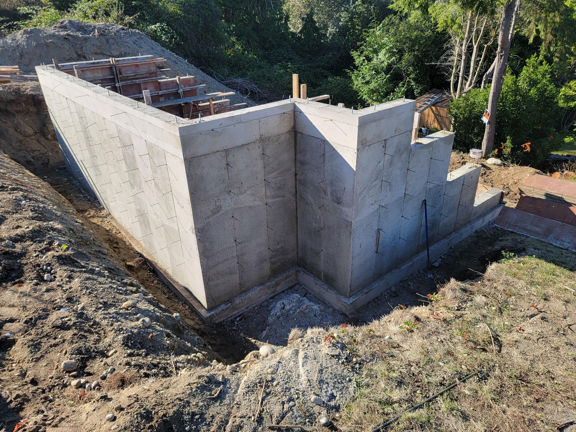 A concrete wall is being built on top of a dirt hill.