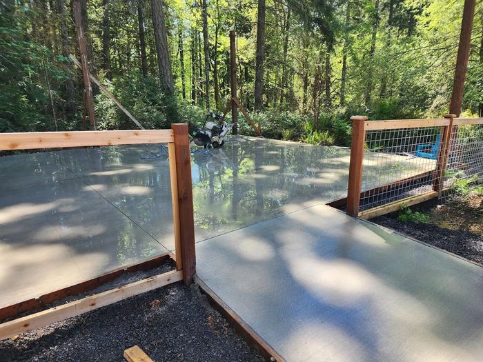 a wooden fence surrounds a concrete walkway in the woods