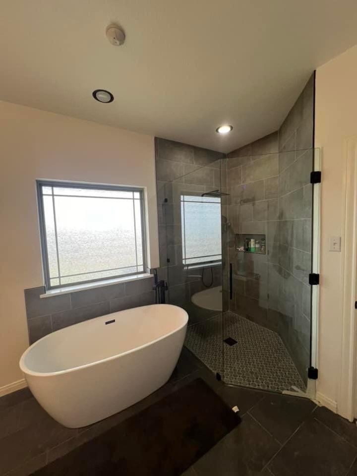 Modern bathroom with freestanding tub, walk-in glass shower, and frosted window