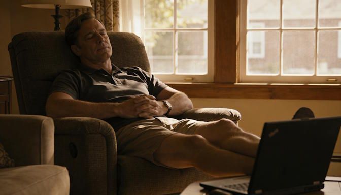 Relaxed male client in Reynoldsburg living room reclining in easy chair, hands folded, serene expression, laptop on coffee table