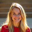 A blonde woman wearing a red shirt is smiling for the camera