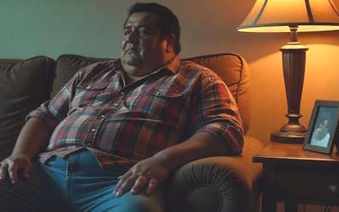 overweight man in Columbus OH sitting on his couch feeling depressed with a sad look on his face