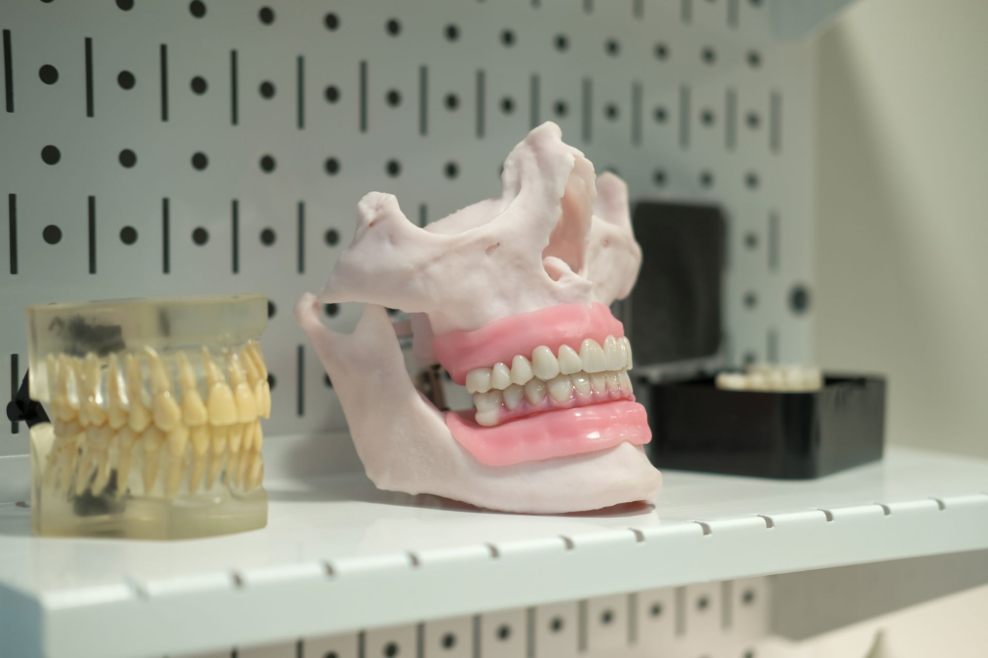 Woman smiles at her teeth in a mirror at the dentist. A panoramic x-ray is visible on a monitor.