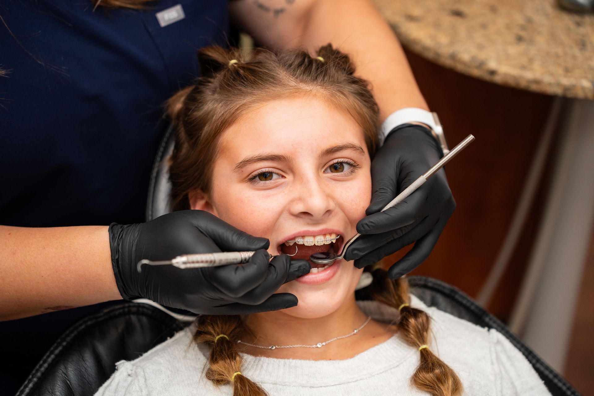 Woman smiling as dentist compares veneer shades to her teeth.