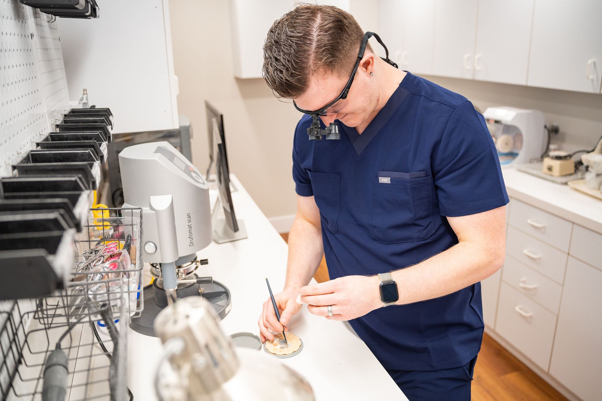 Woman holding a dental shade guide to match tooth color; smiling.