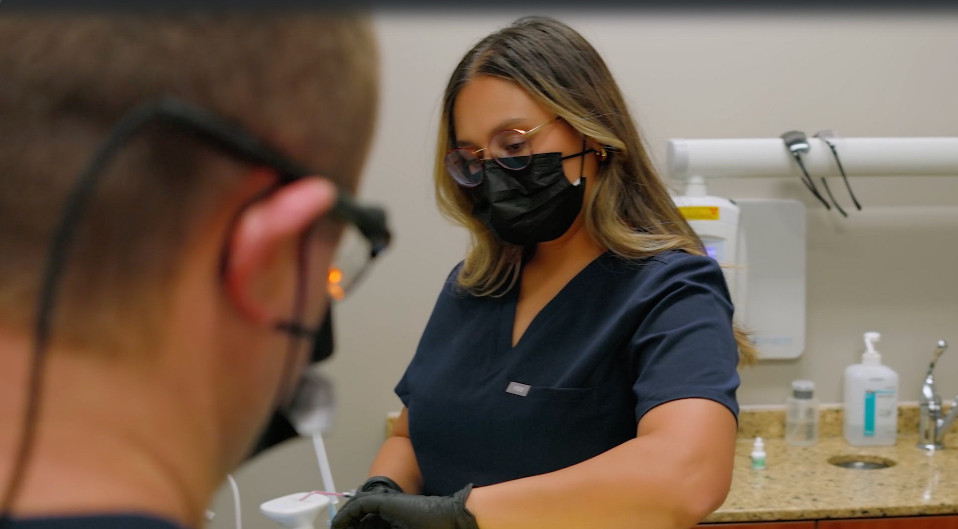Dentist showing teeth model to patient. Both are smiling. Dental office setting.