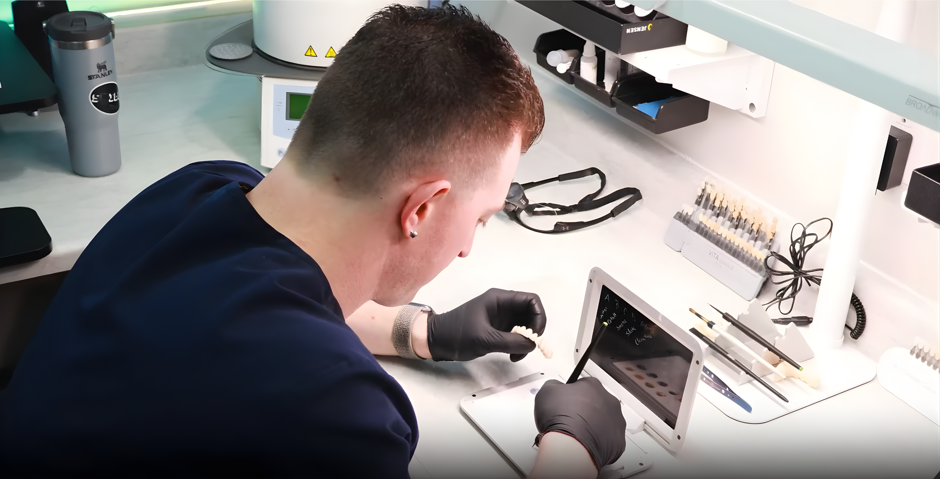 Dental bridge with three implants, featuring pink gums and white teeth, reflected on a black surface.