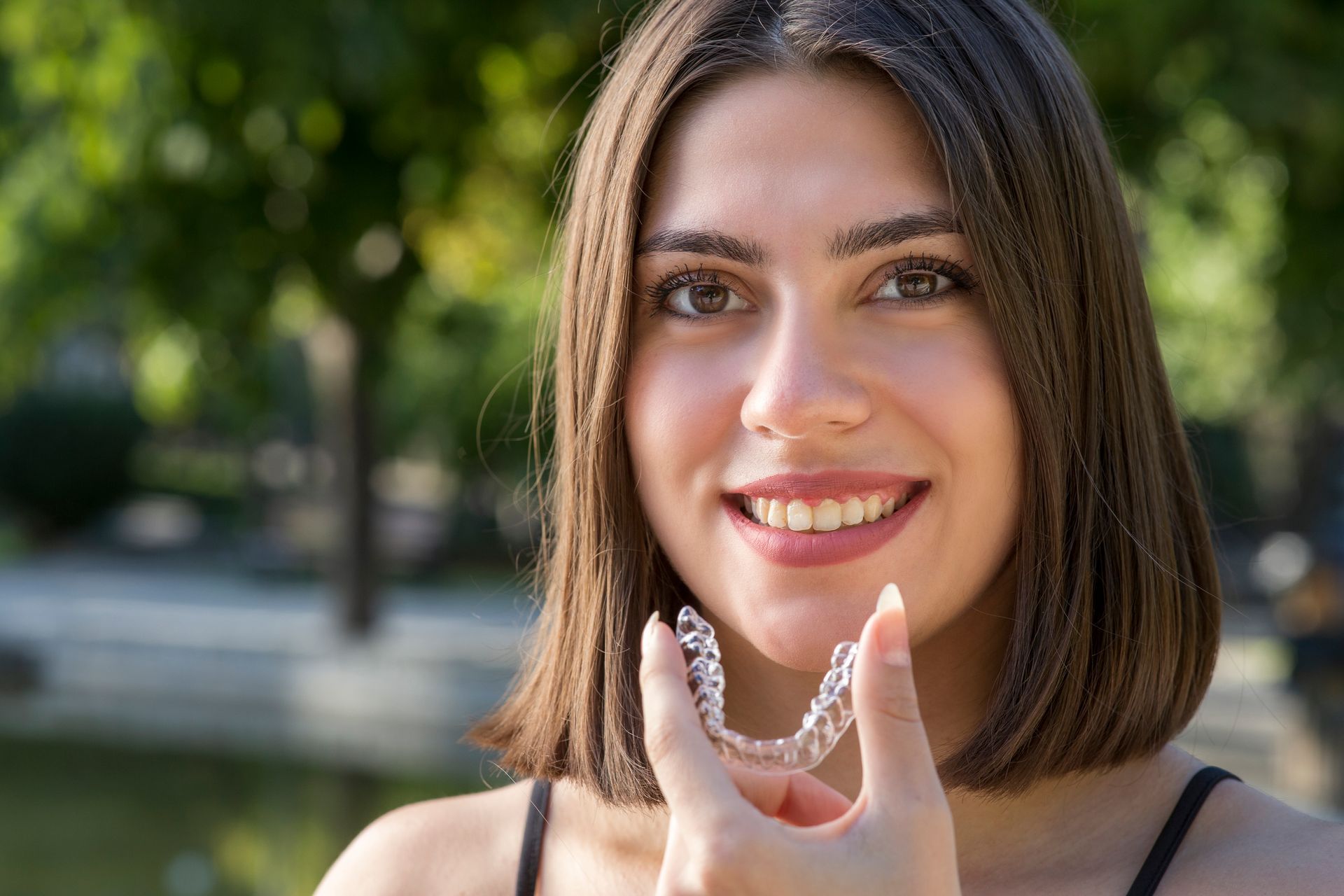 Dentist holding clear aligner, explaining to smiling patient in clinic setting.