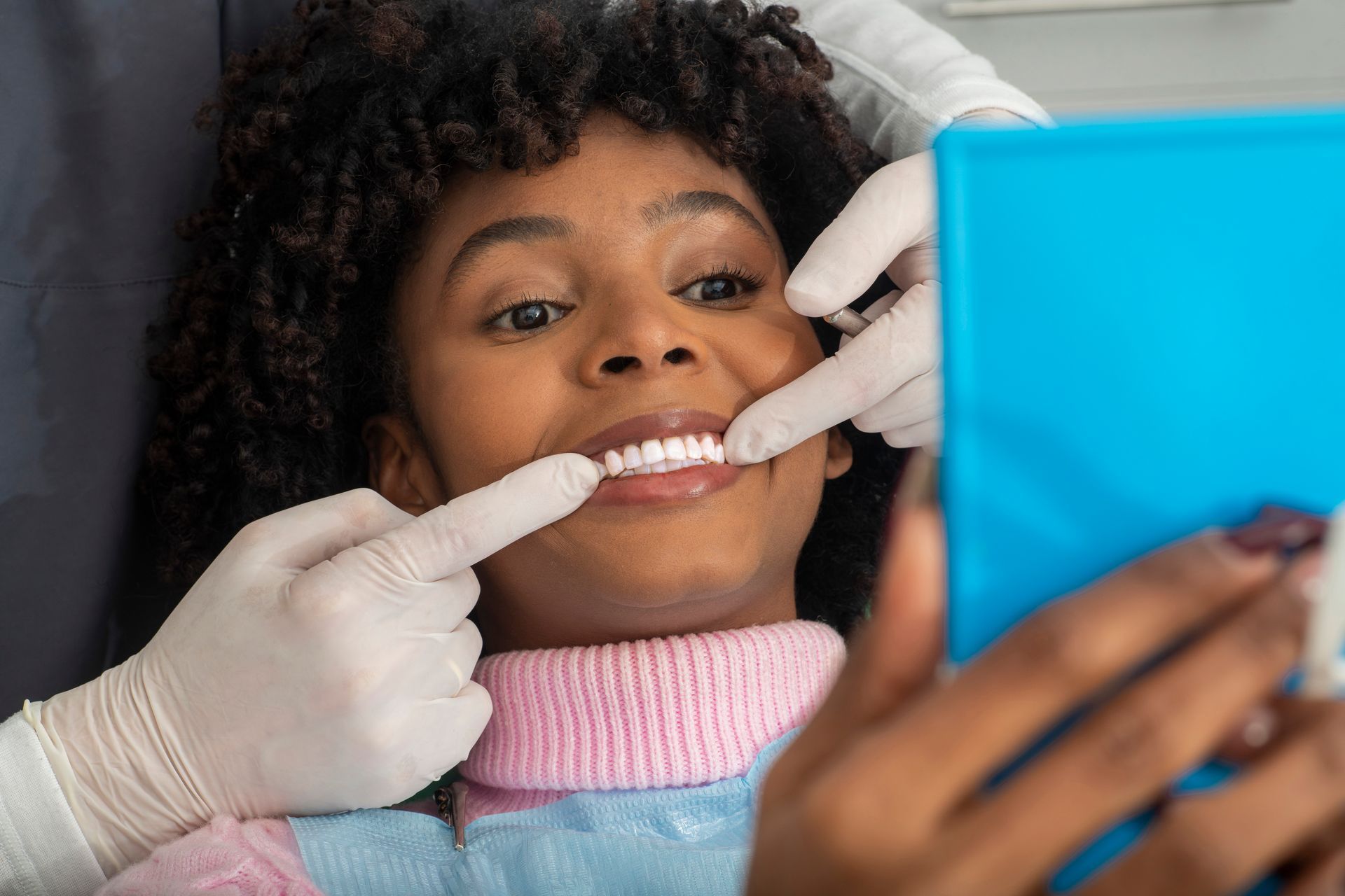 Hands holding two clear Invisalign aligners, against a blurred background.