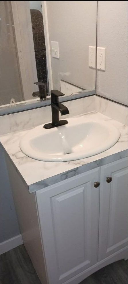 A bathroom sink with a black faucet and a mirror.