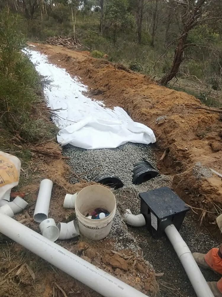 A Bunch of Pipes and a Bucket Are Laying on the Ground — Simon Dickson Excavations in Moss Vale, NSW