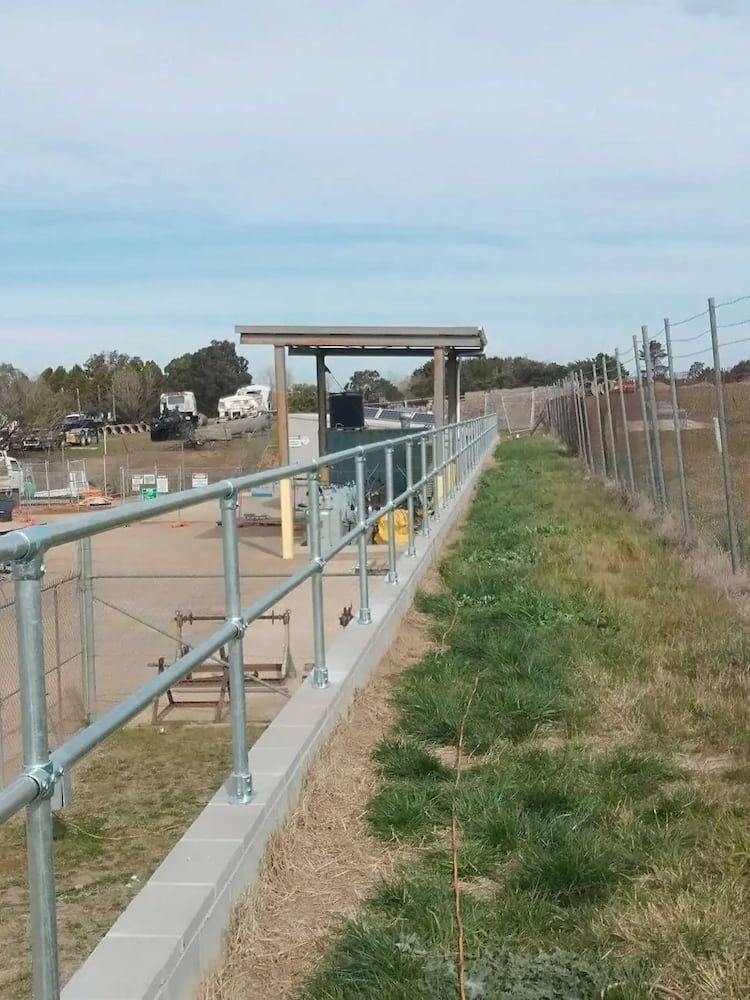 A Fence with a Metal Railing is Surrounded by Grass and Dirt — Simon Dickson Excavations in Moss Vale, NSW