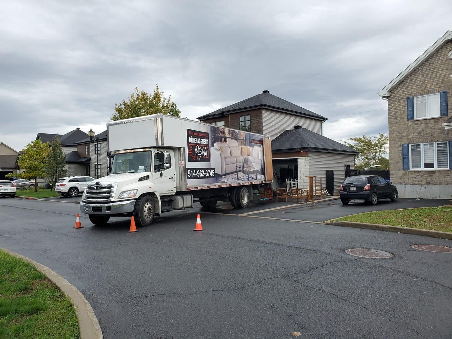 Un camion blanc roule dans une rue devant une maison.