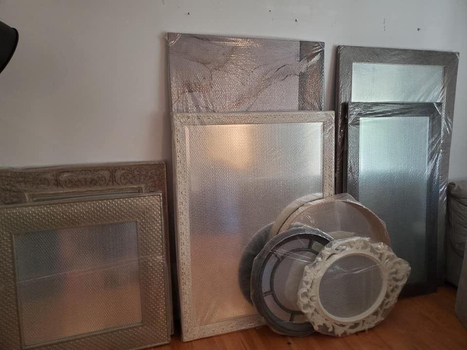 Un tas de miroirs sont posés sur un plancher en bois.