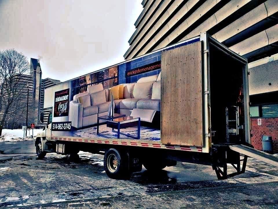 Un camion avec une photo d'un canapé sur le côté est garé devant un bâtiment.