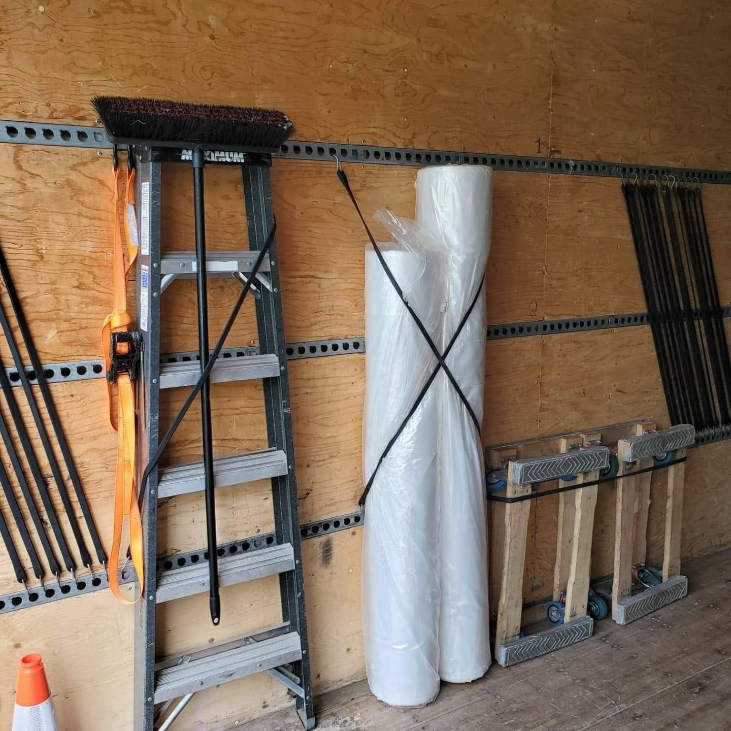 Une échelle est appuyée contre un mur à côté d'un balai