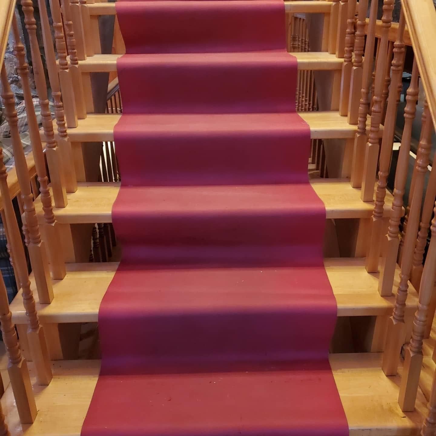 Un escalier en bois avec un tapis rouge sur les marches.