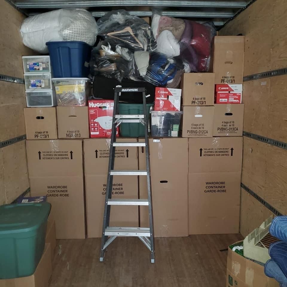 Une échelle se trouve dans une pièce remplie de boîtes, dont une sur laquelle est écrit Huggies