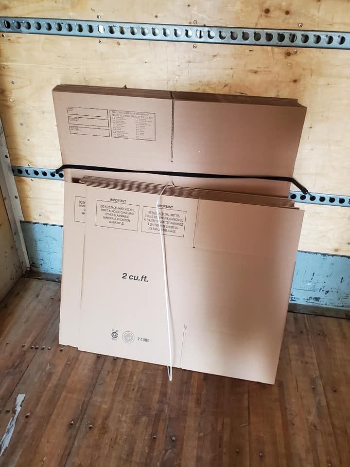 Deux boîtes en carton sont empilées l'une sur l'autre sur un plancher en bois.