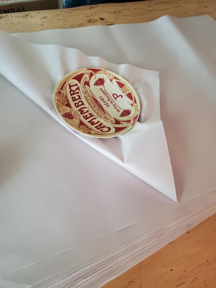 Un pot de fromage est posé sur une pile de papier blanc.