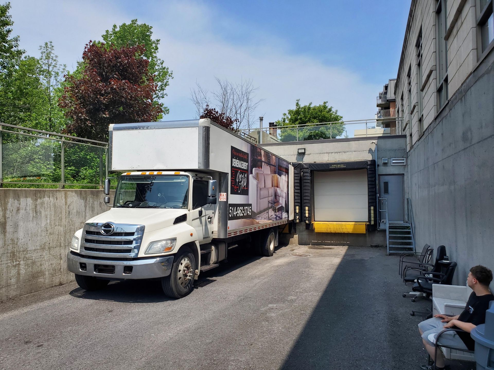 Un camion blanc est garé sur un parking à côté d'un bâtiment.