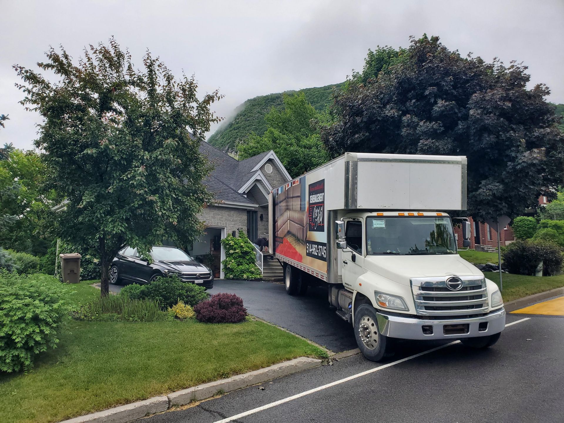 Un camion de déménagement est garé devant une maison au bord de la route.