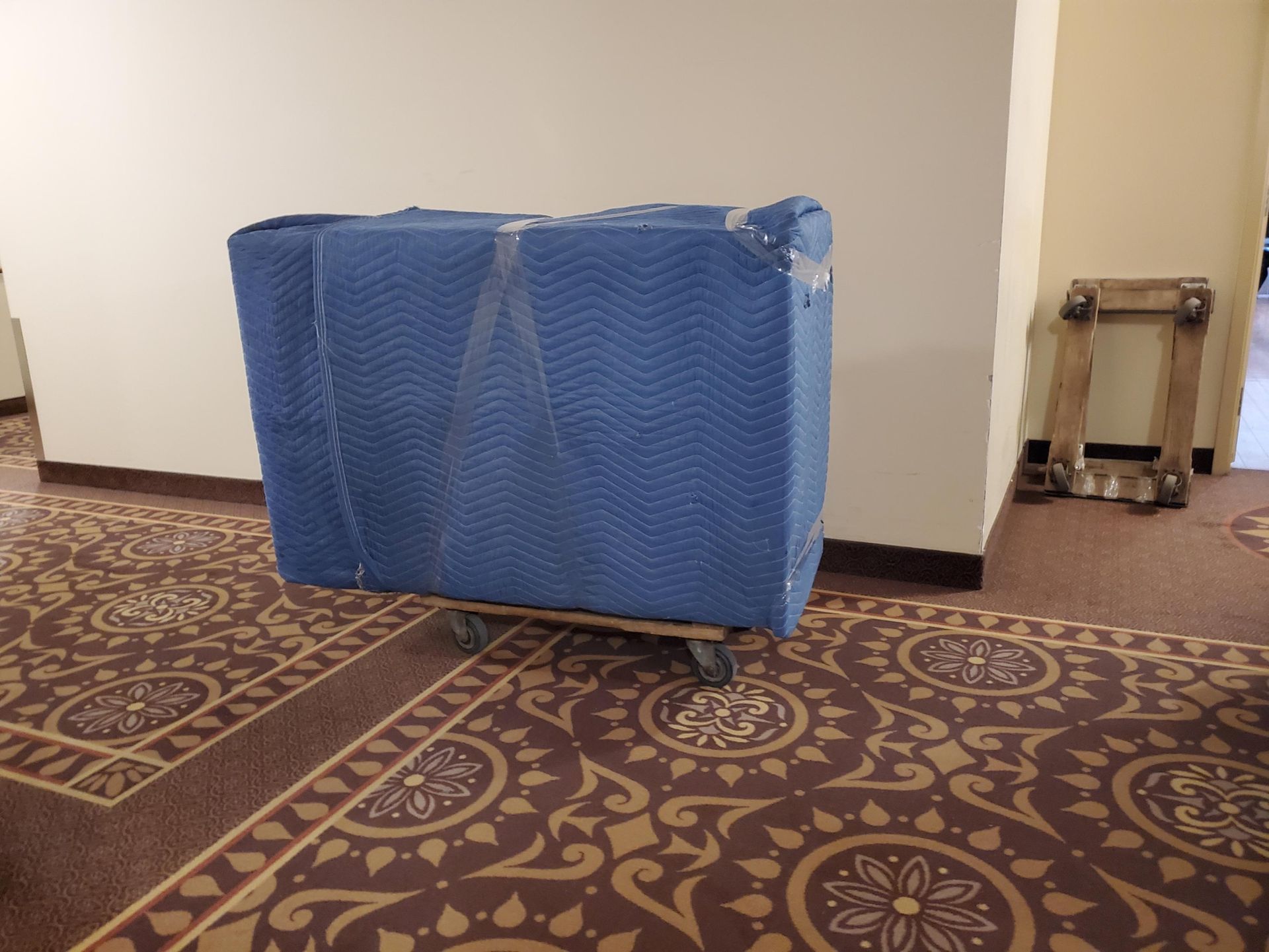 Une boîte bleue est posée sur un chariot dans un couloir.