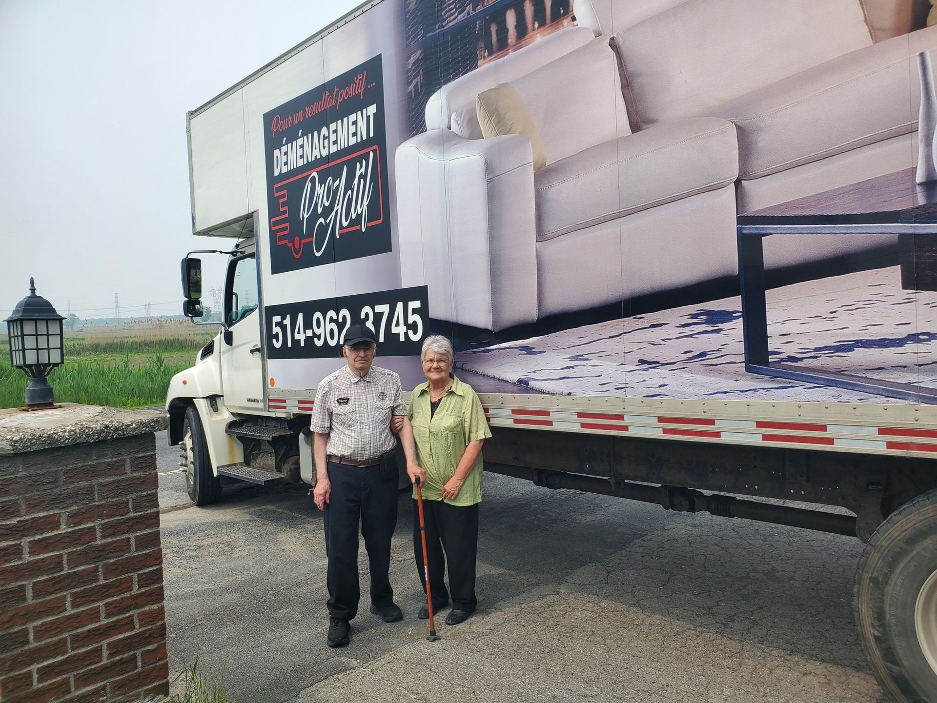 Un homme et une femme debout devant un camion de déménagement