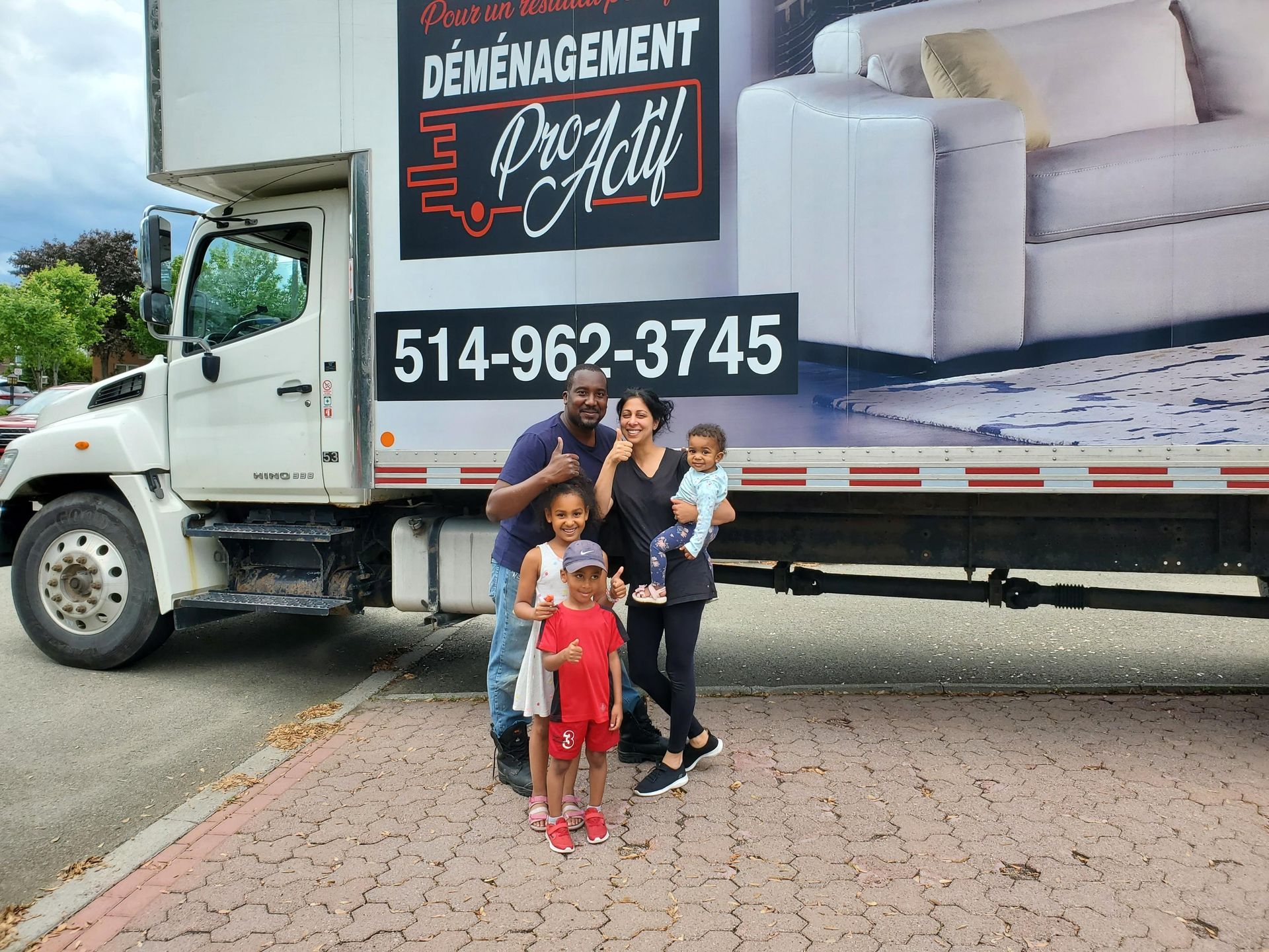 Une famille se tient devant un camion de déménagement.