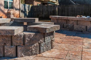 A brick fire pit is sitting on top of a brick patio.