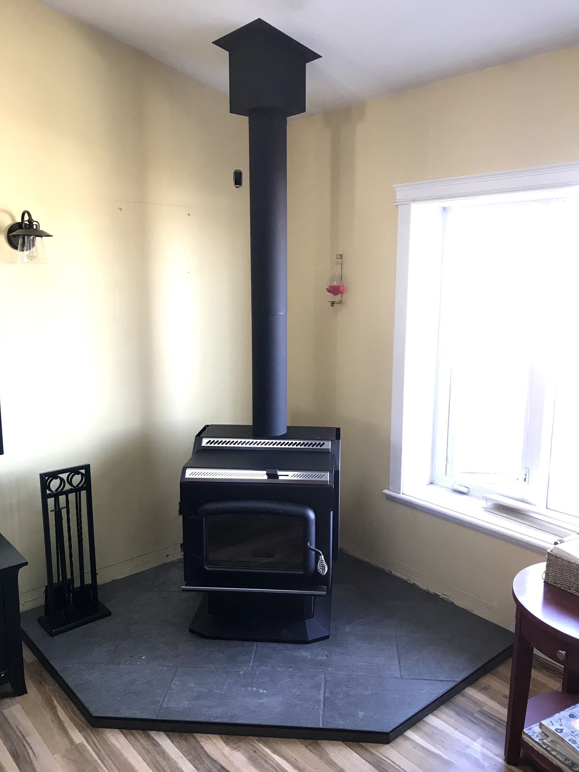A wood stove is sitting in a living room next to a window.