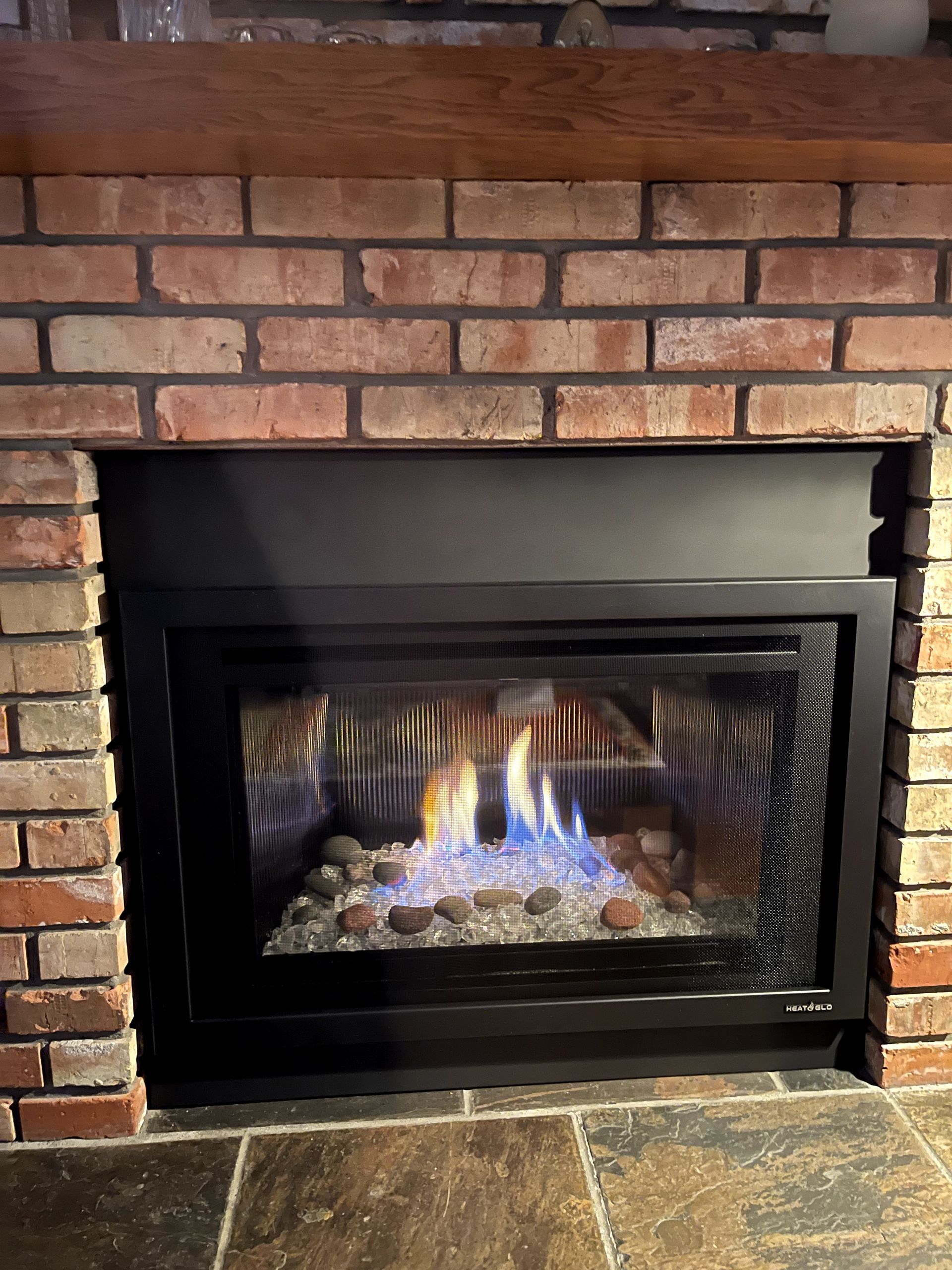 A gas fireplace is built into a brick fireplace.