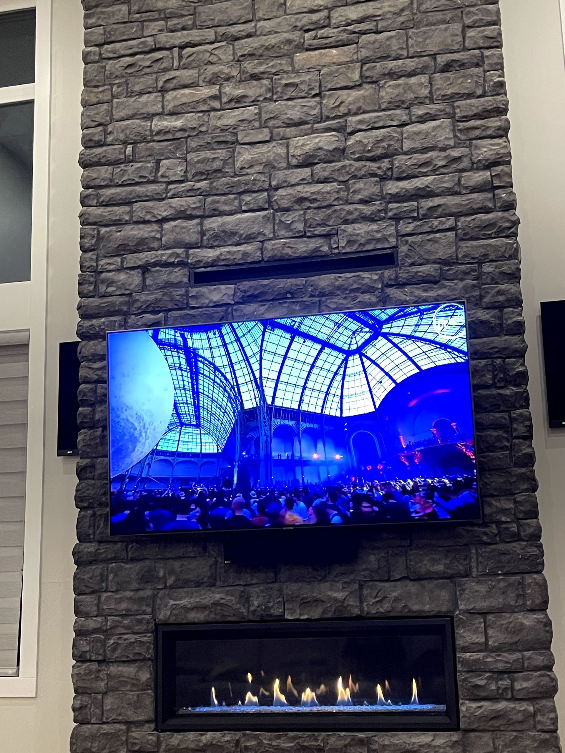 A flat screen tv is mounted on a brick wall above a fireplace.