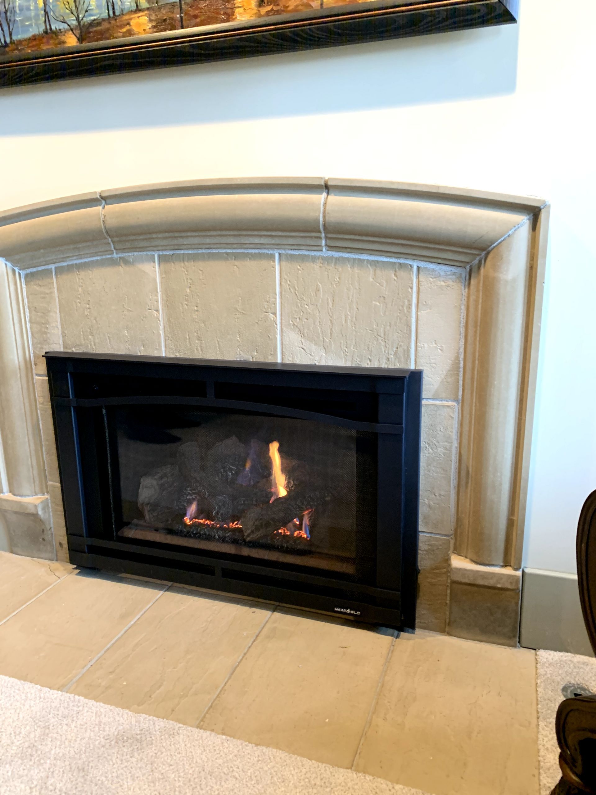 A fireplace is sitting in a living room next to a chair.