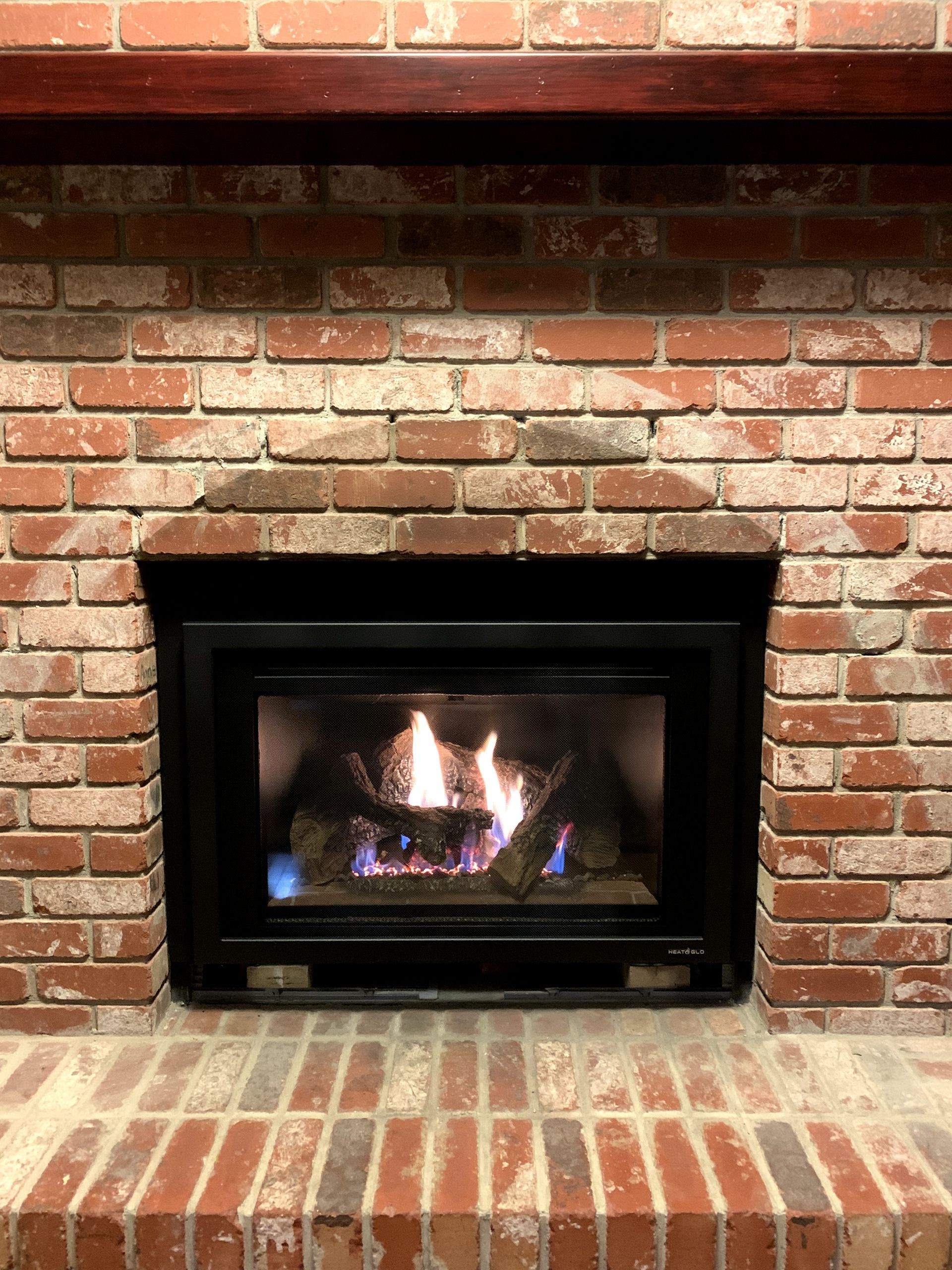 A gas fireplace is built into a brick wall.