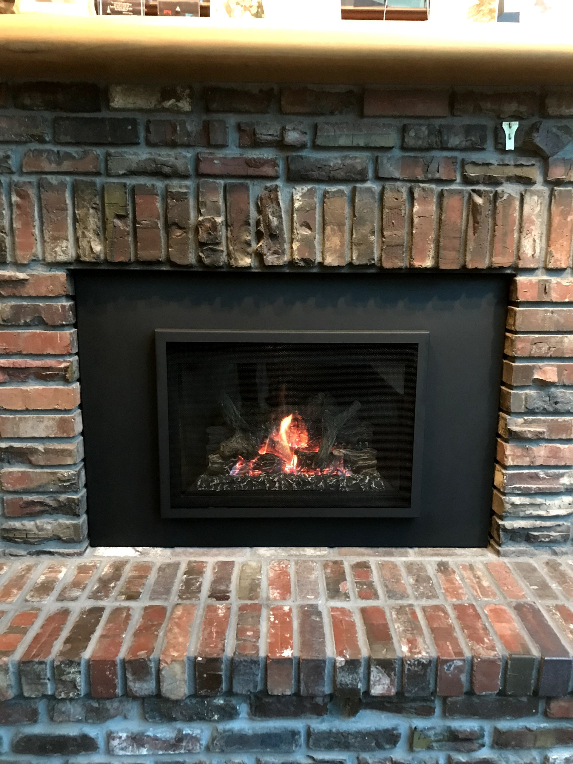 A brick fireplace with a gas fireplace insert in it.