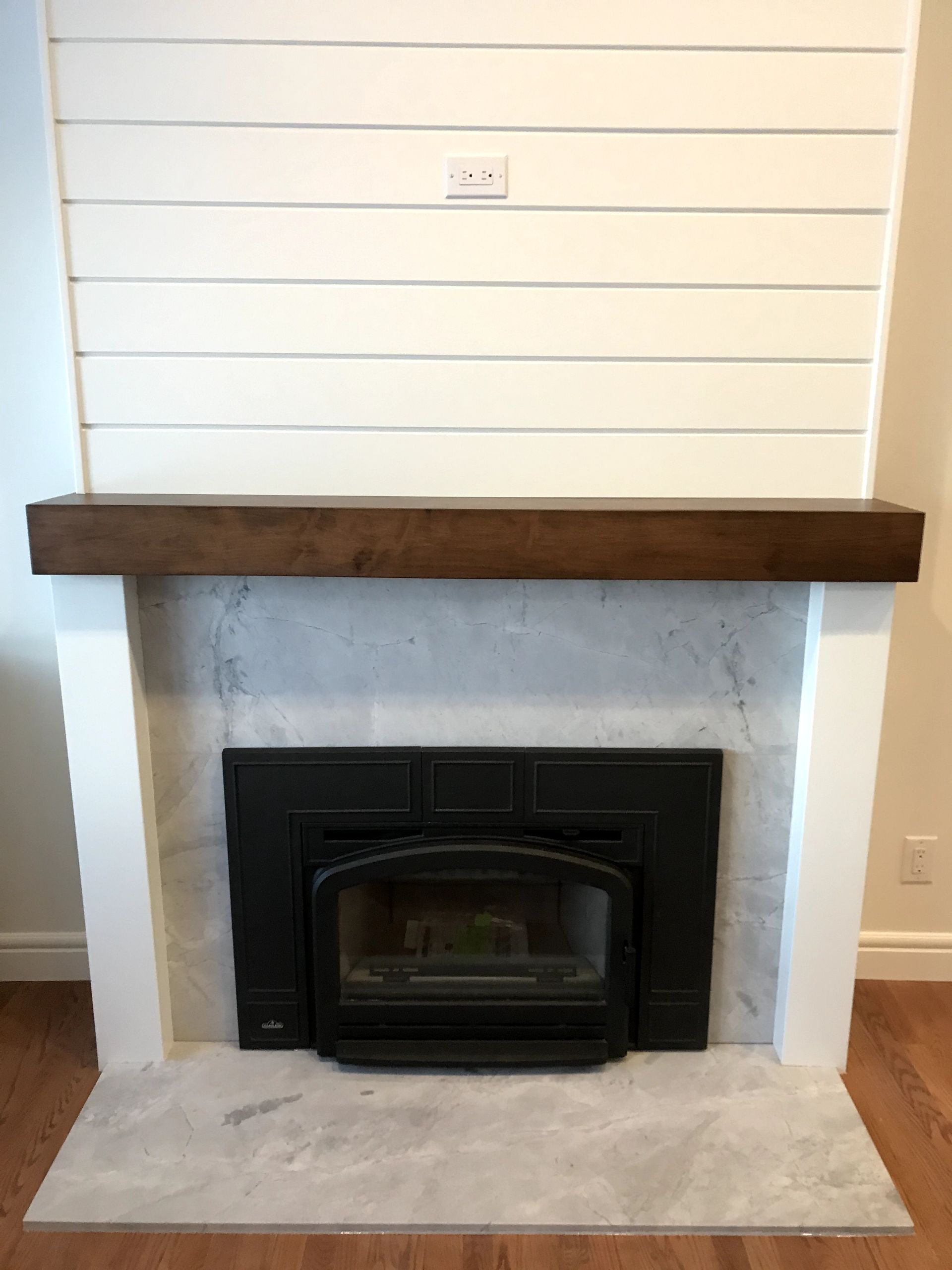 A fireplace with a wooden mantle in a living room.