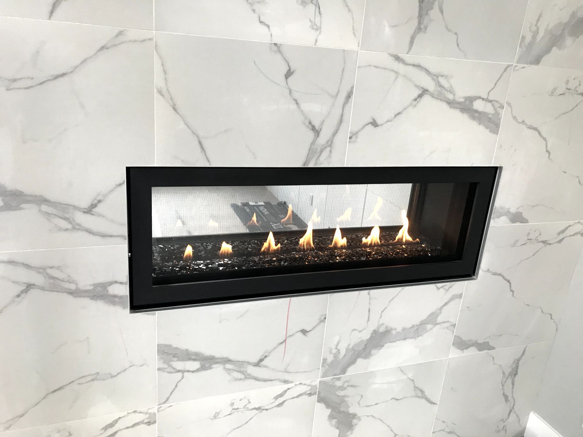 A fireplace is built into a marble wall.