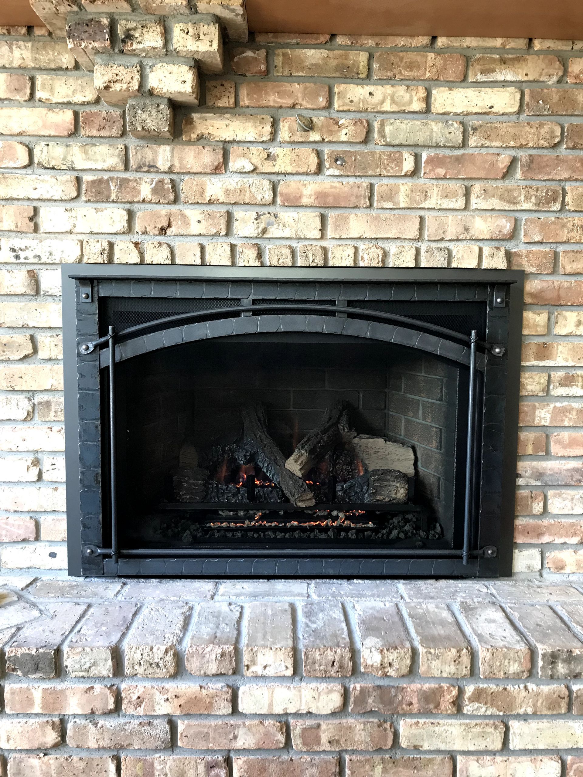 There is a fireplace in the middle of a brick wall.