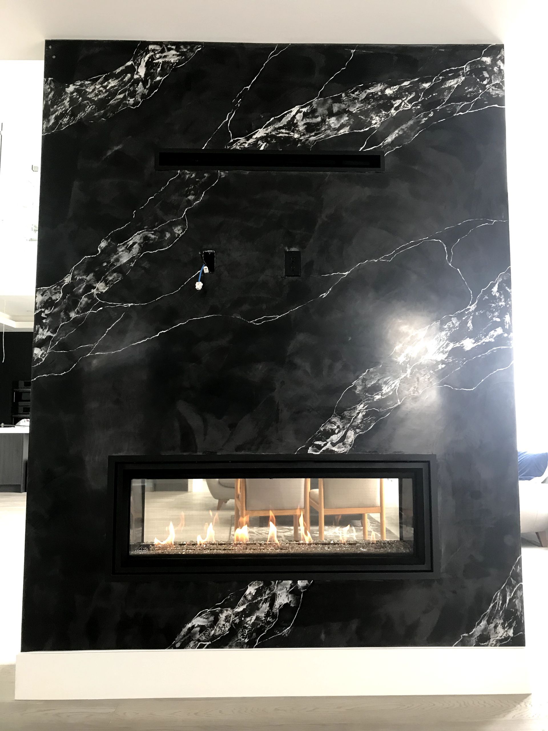 A fireplace with a black and white marble wall