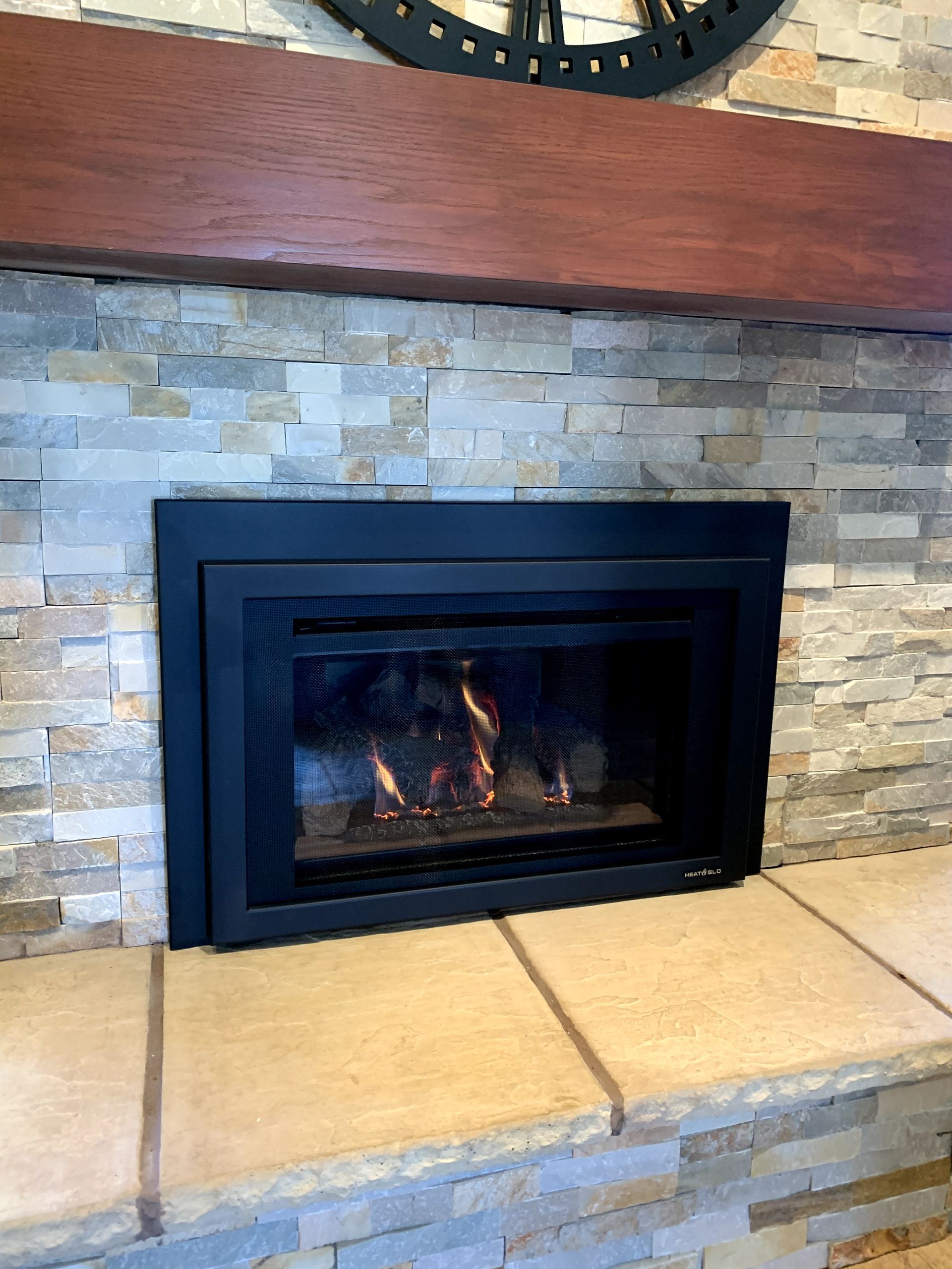 A fireplace with a clock above it in a living room.
