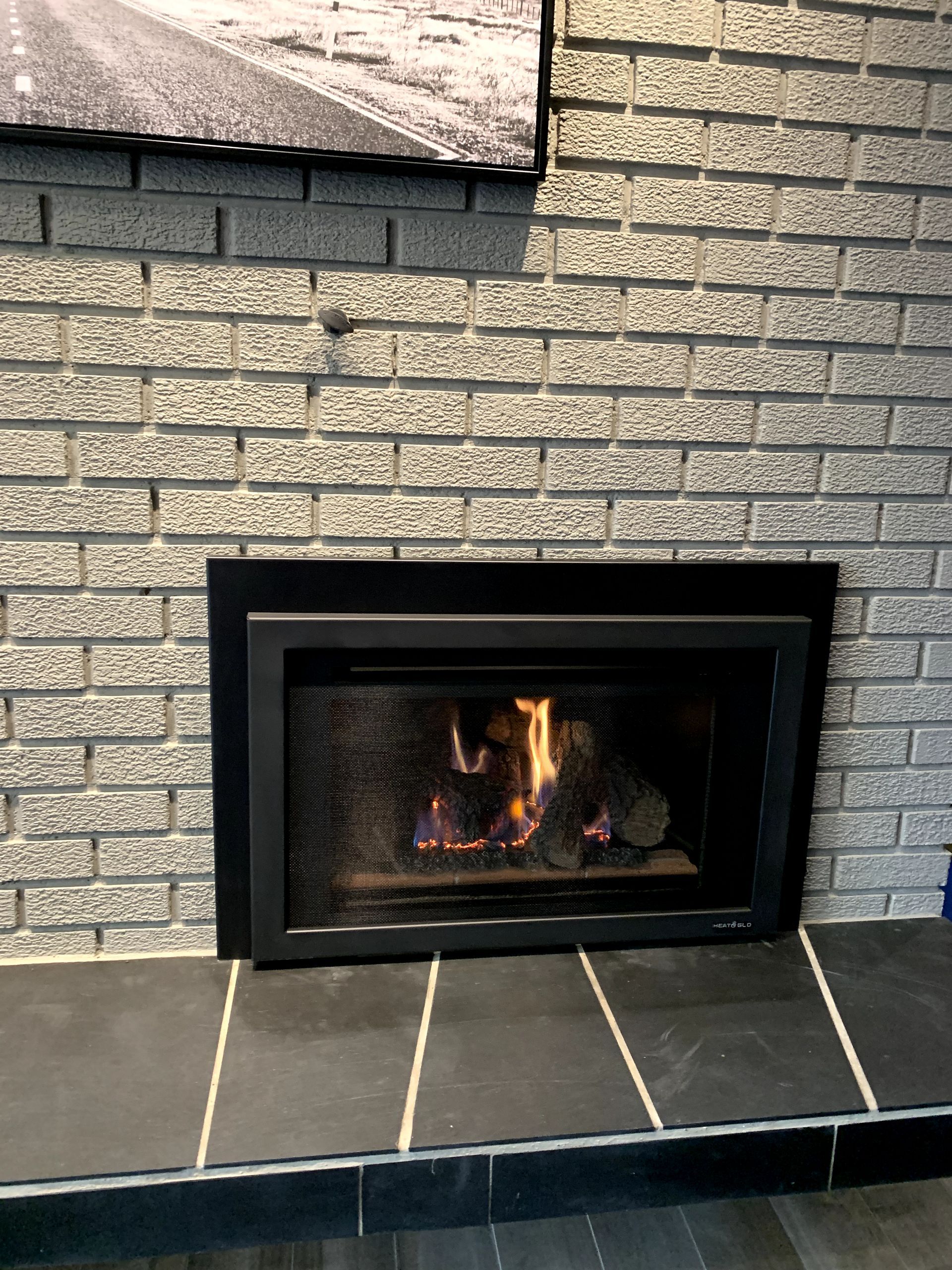 A gas fireplace is built into a brick wall.