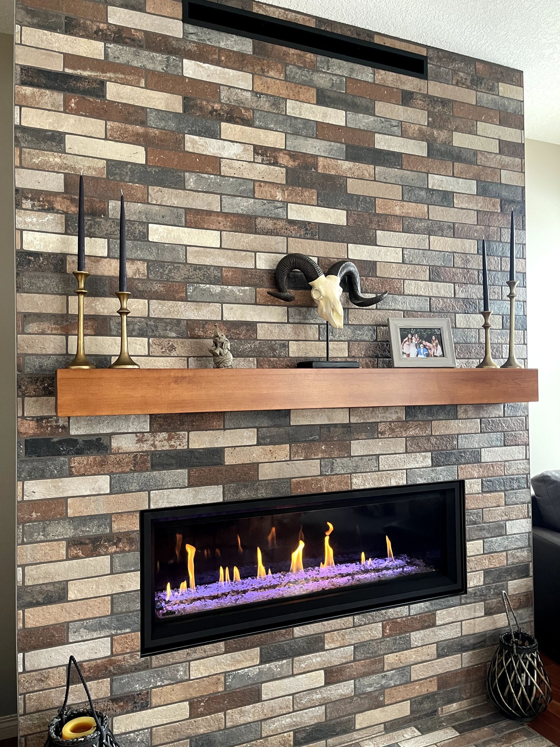A fireplace with a brick wall and a wooden mantle in a living room.
