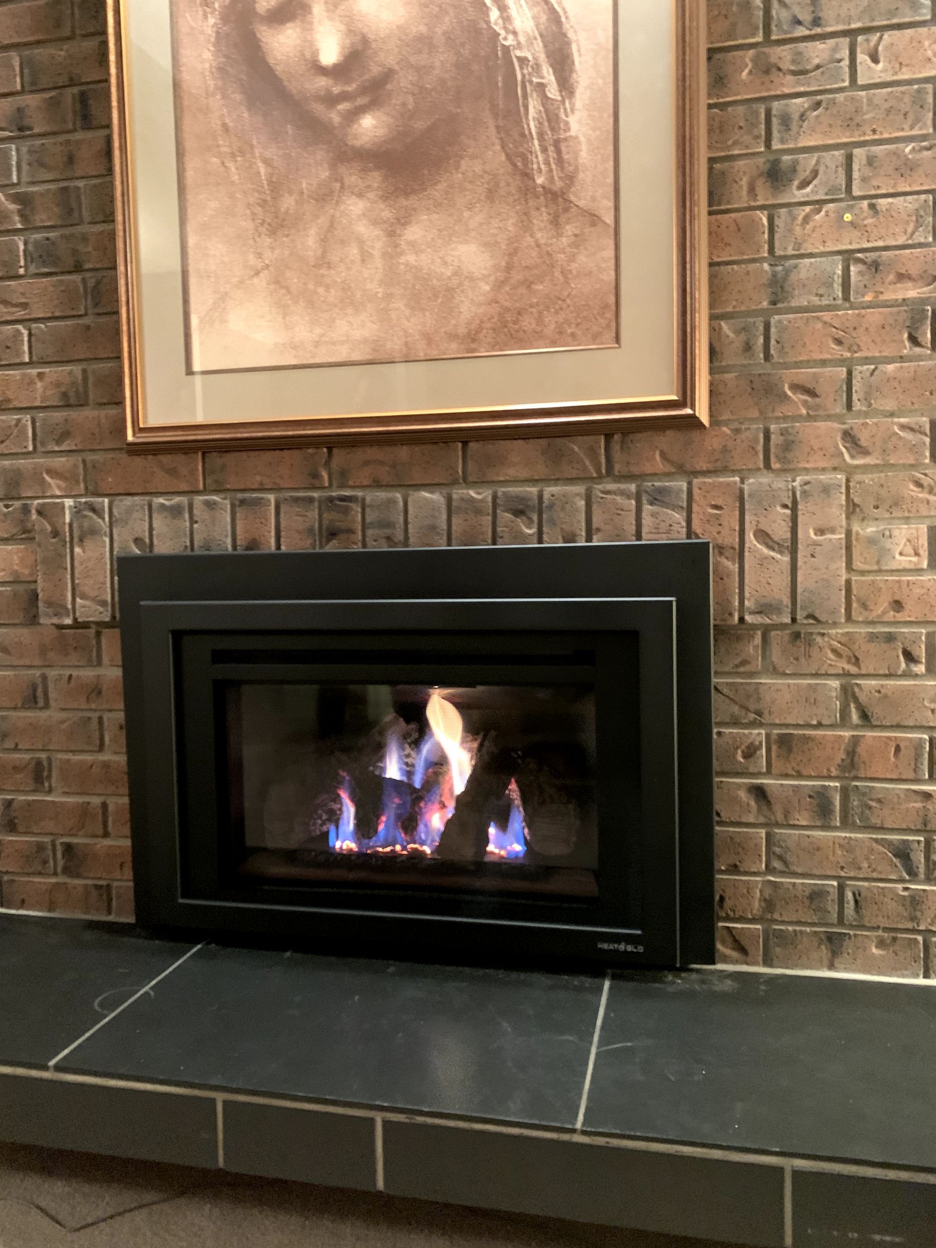A fireplace with a picture of a woman above it