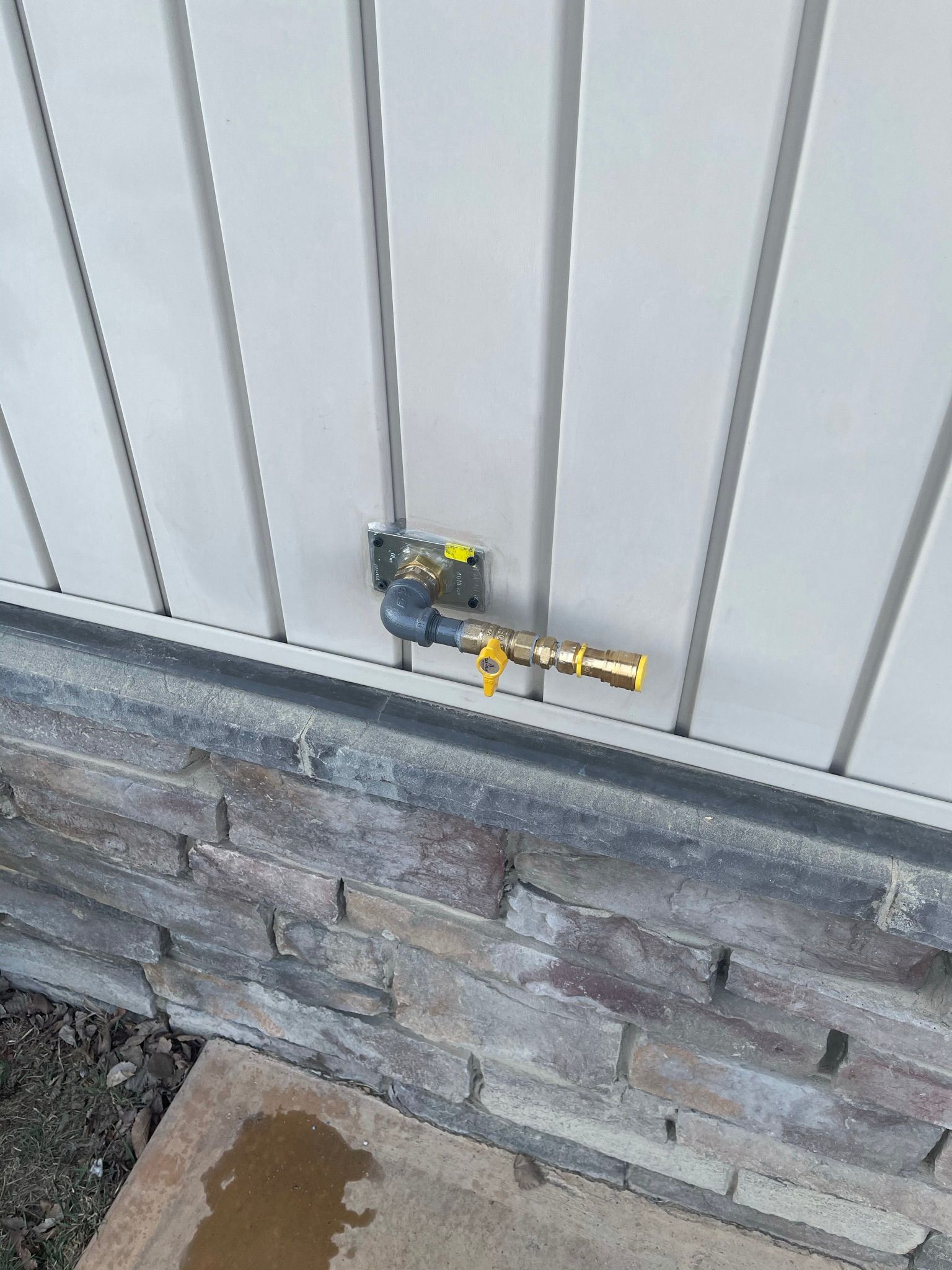 A hose is attached to a wall next to a brick wall.