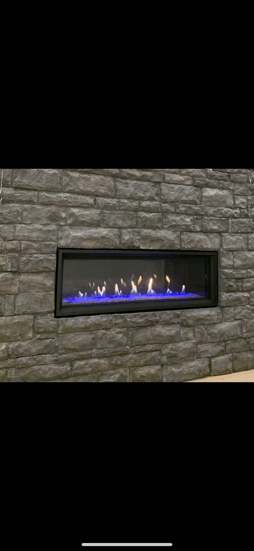 A fireplace with blue flames is built into a brick wall.