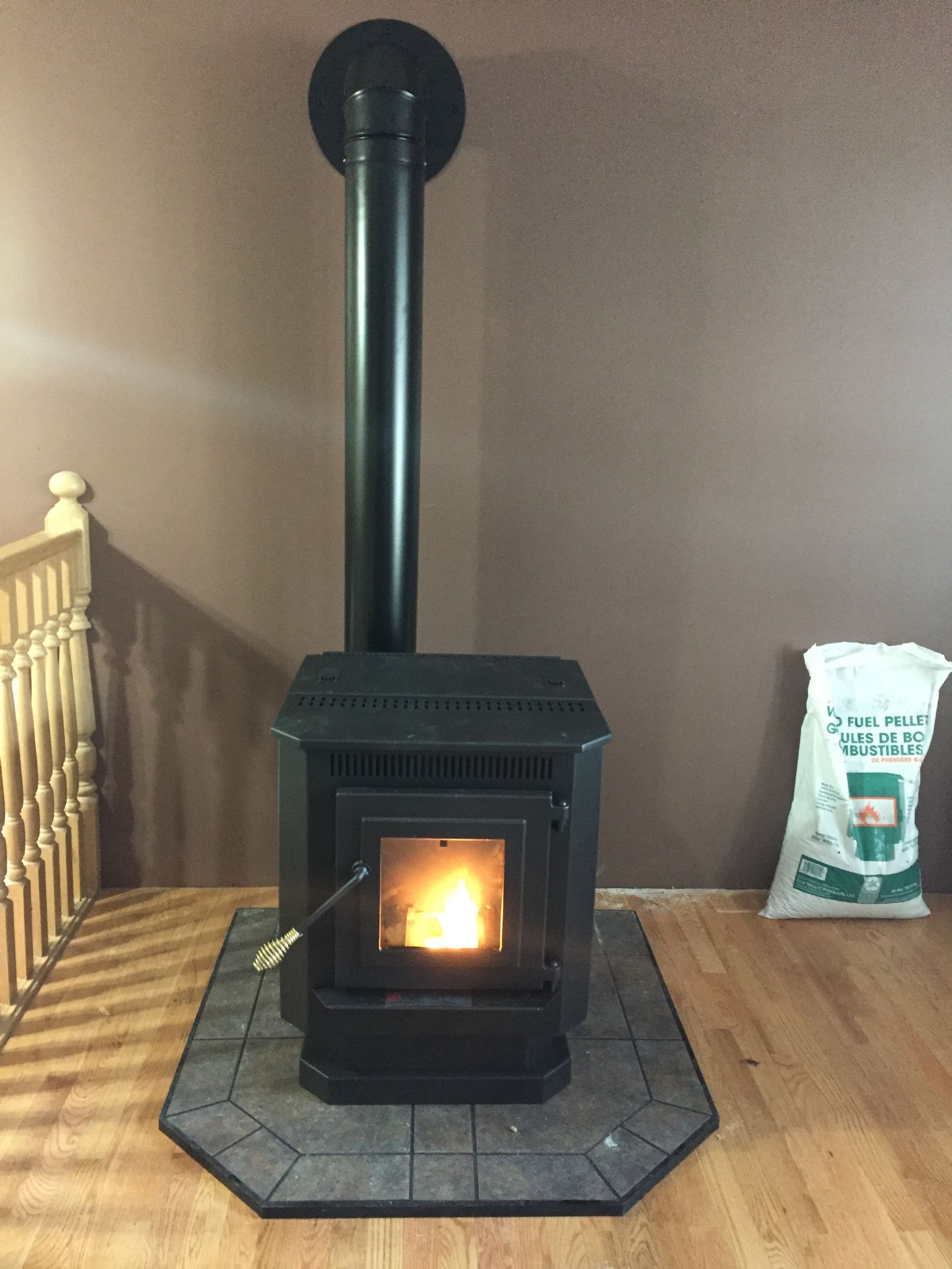 A wood stove is sitting in a room next to a bag of wood pellets