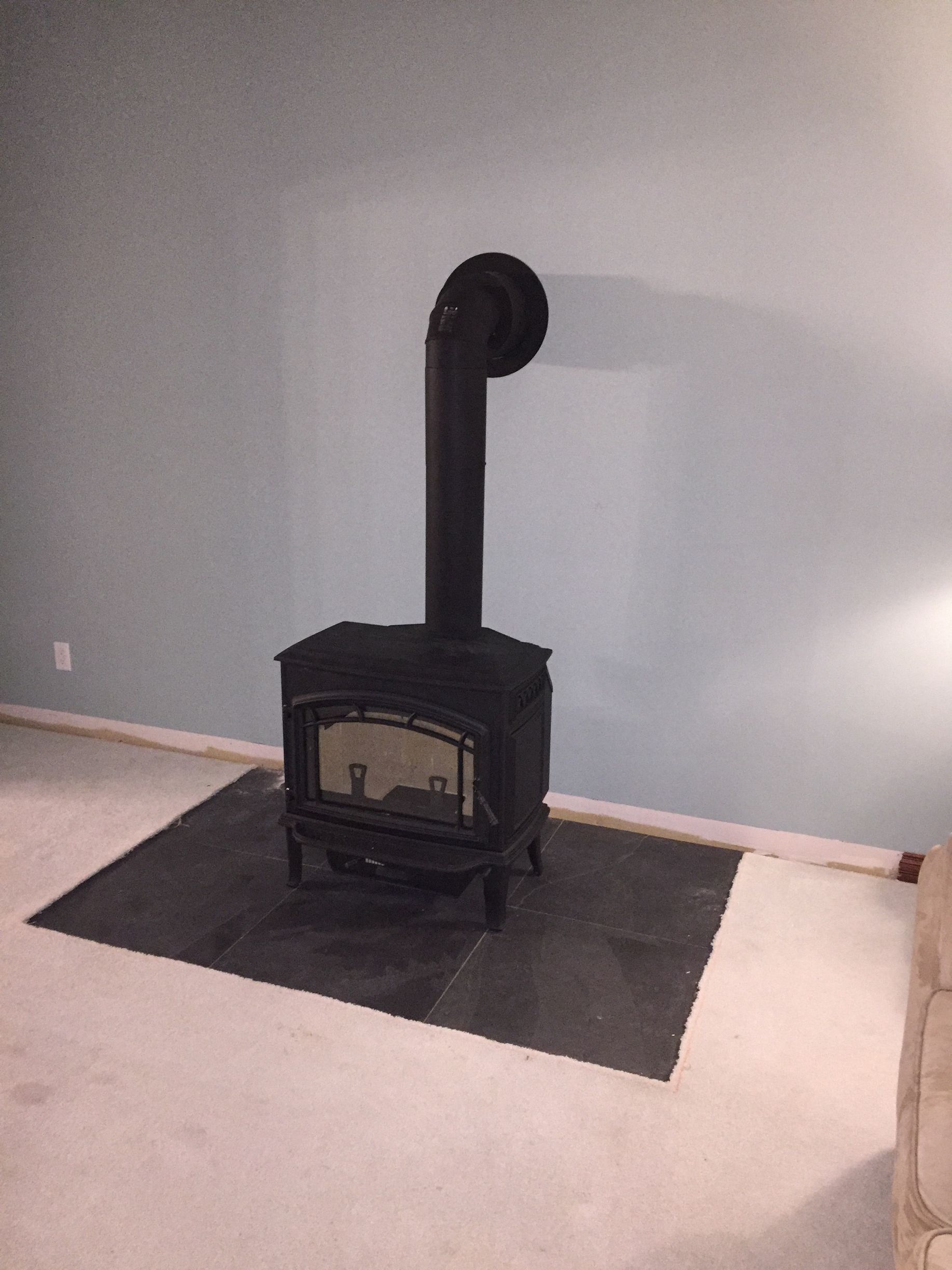 A wood stove is sitting on the floor in a living room.