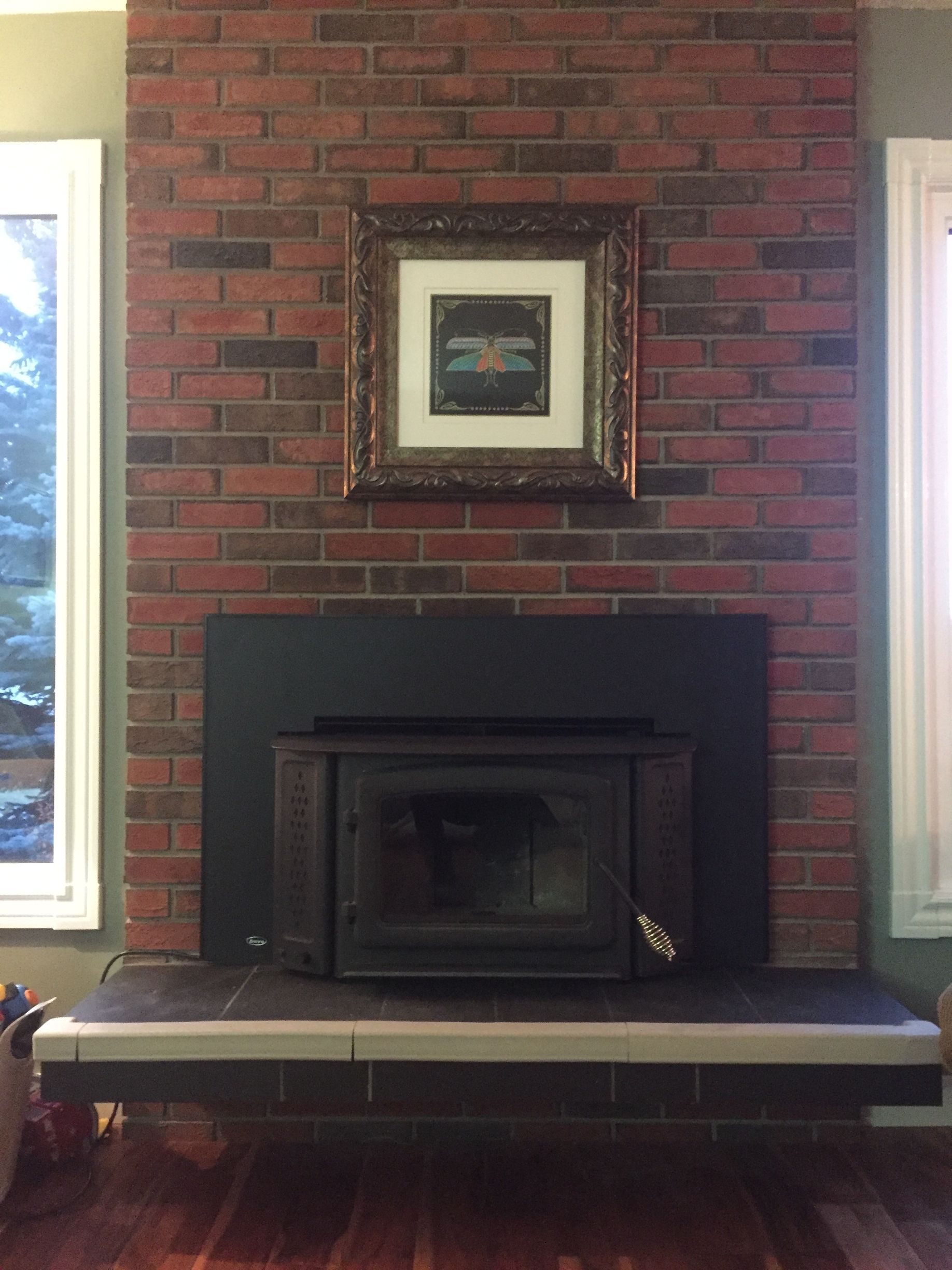 A brick fireplace with a picture above it