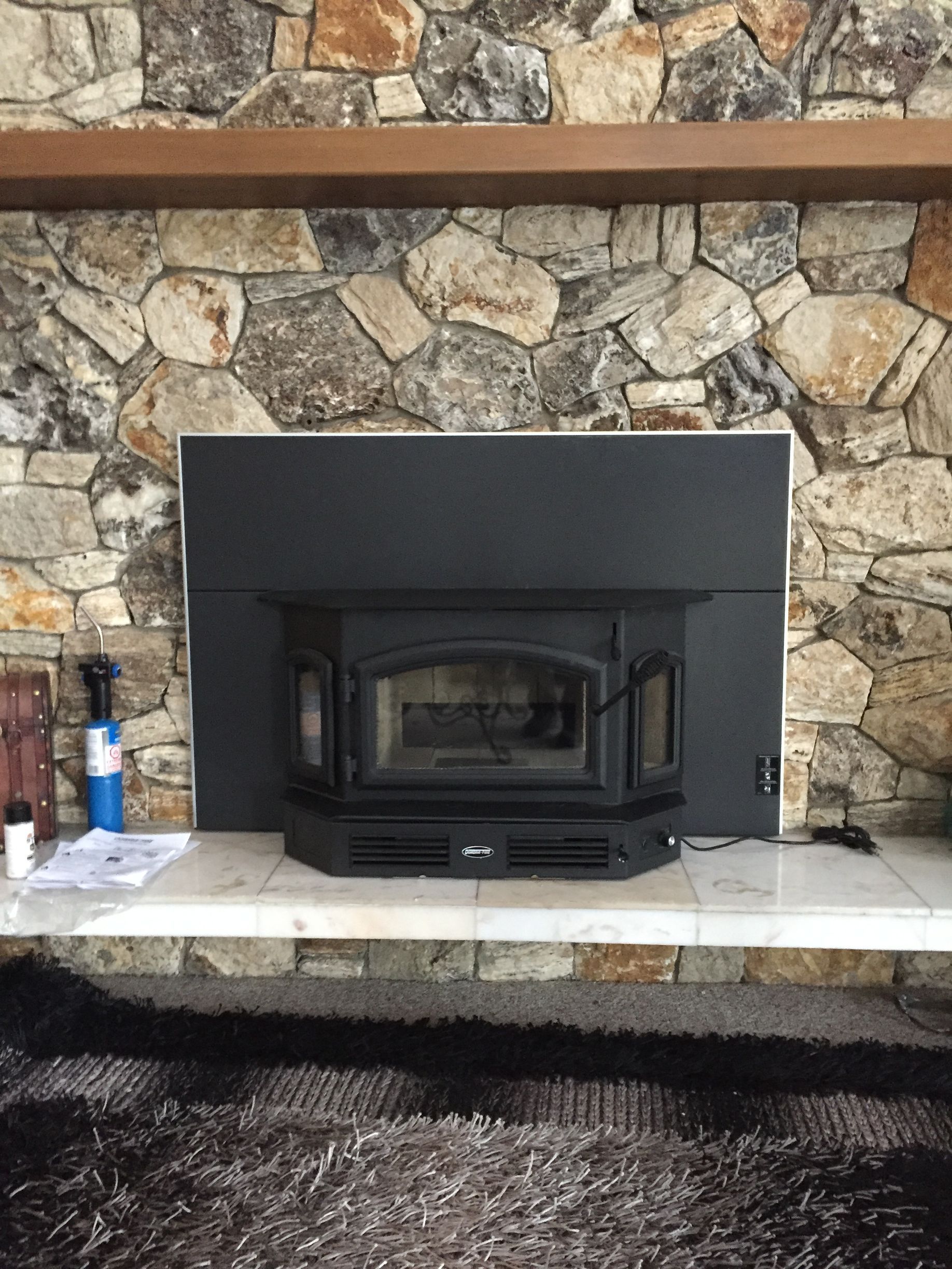 A fireplace in a living room with a stone wall.